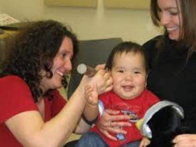 photo of specialist checking on infant held by his mother