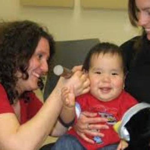 photo of specialist checking on infant held by his mother