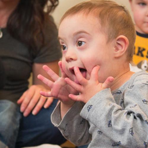 photo of infant with hands on his face