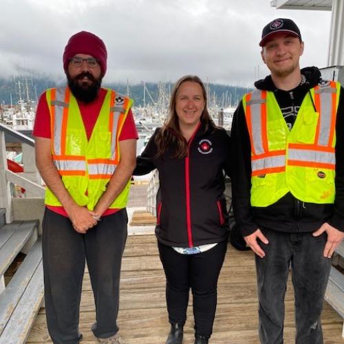 Three individuals standing on a dock smiling and posing for photo on first day of work.
