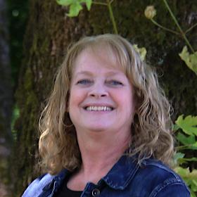 A picture of a woman in a jean jacket smiling