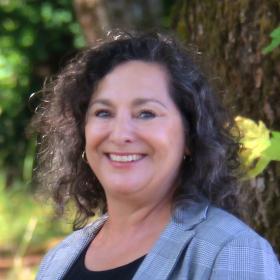 A woman in a grey blazer smiling
