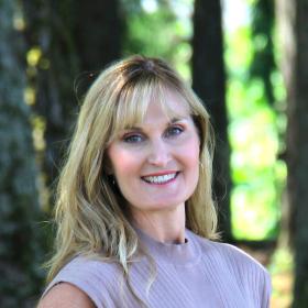 A woman in a beige shirt smiling